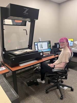 Image of student employee Madison Northup seated at book scanner.